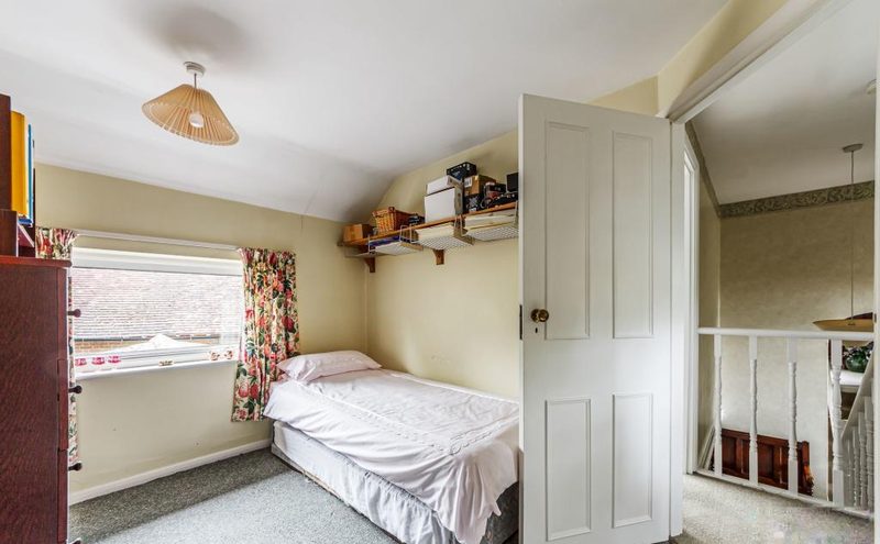 A smaller bedroom with a single bed, sloped ceiling and a window to the garden.