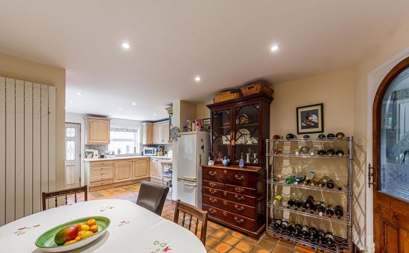 A round table with fruit, a dresser and a doorway through to the kitchen beyond.
