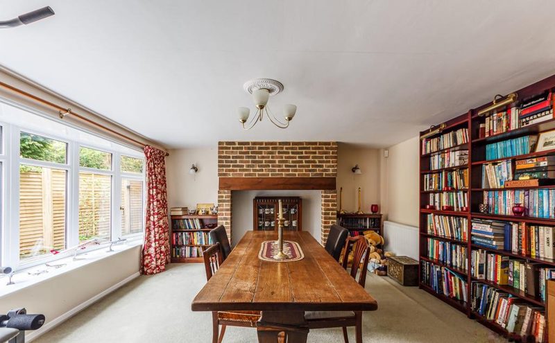 The dining room from the opposite corner, showing windows, bookshelves and the brick fireplace.