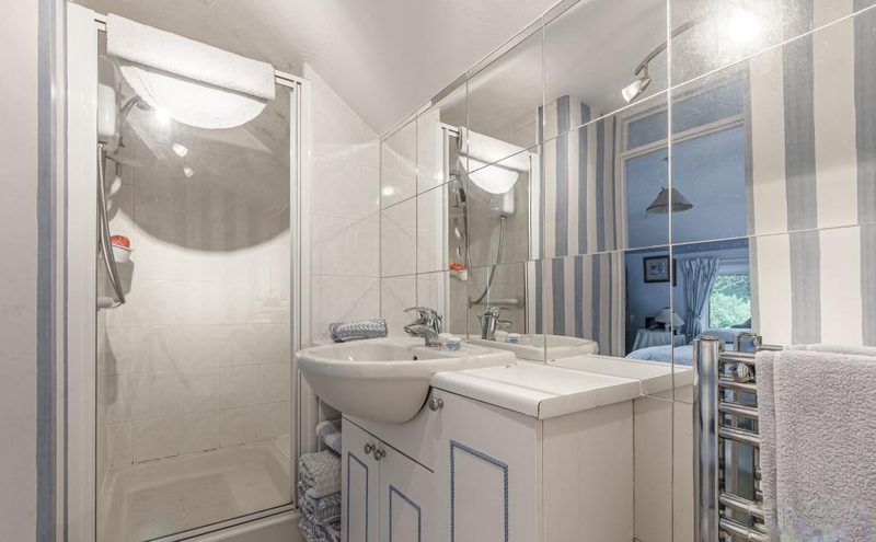 An en-suite shower room with a glazed cubicle, basin and mirrored wall.