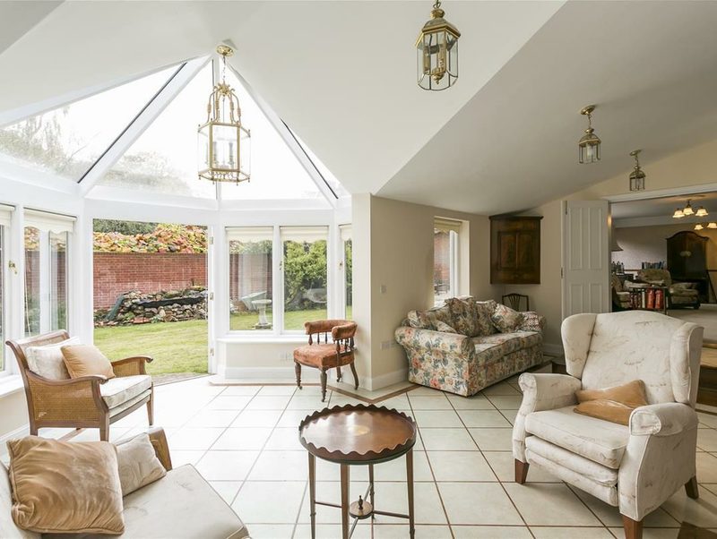 A glazed garden room with a vaulted ceiling, lanterns and doors onto the lawn.